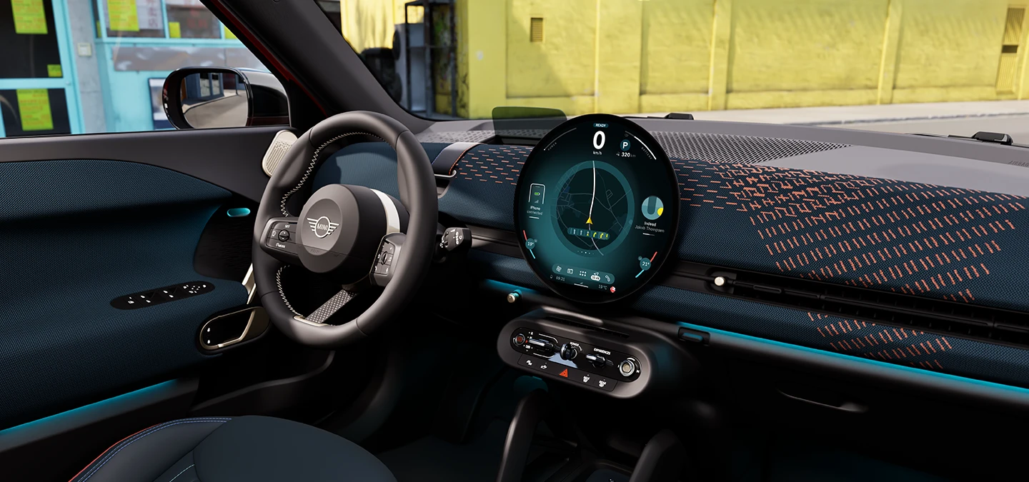 Interior view of the all-electric MINI Aceman with focus on the dashboard, the interaction unit and the steering wheel.