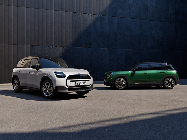 Front and Side view of the all-electric MINI Aceman in Nanuq White and British Racing Green with Black roof on a street.